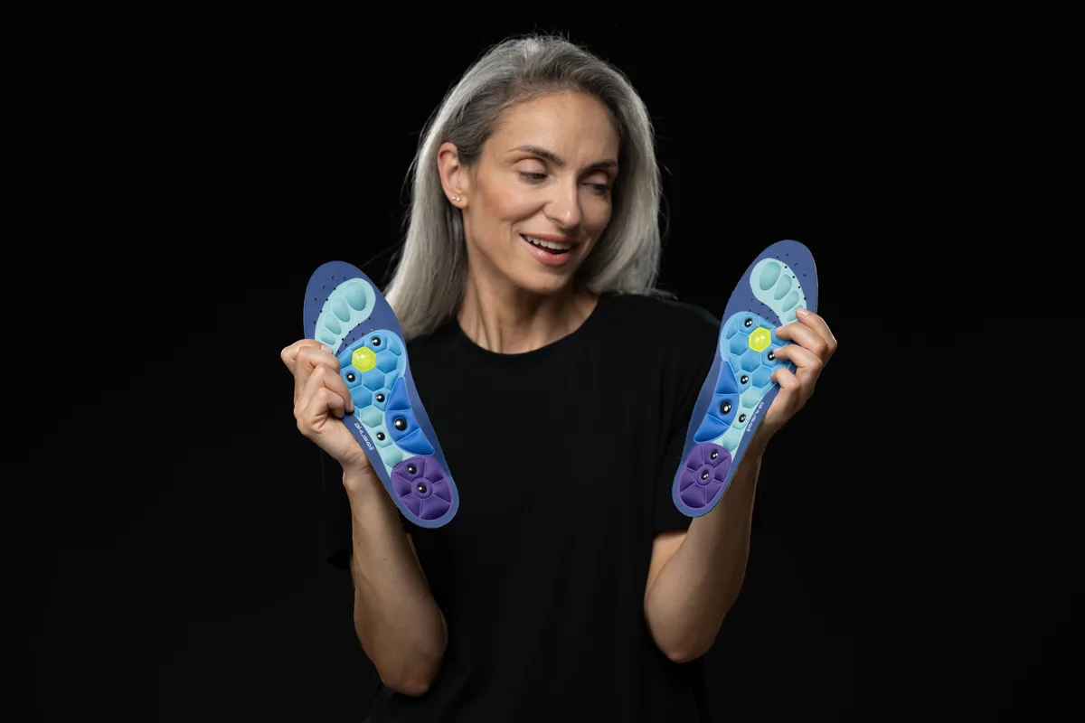 Woman presenting a pair of cushioned insoles